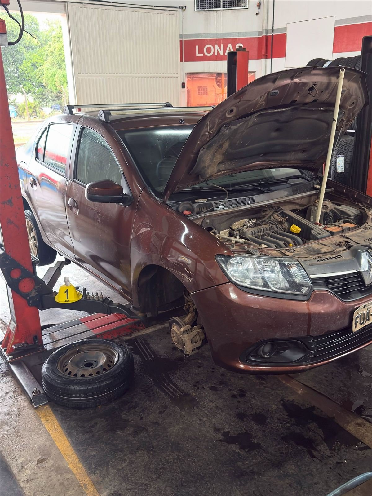 Interior da oficina Carlos Pneus em Piraju com veículos em elevadores e estoque de pneus